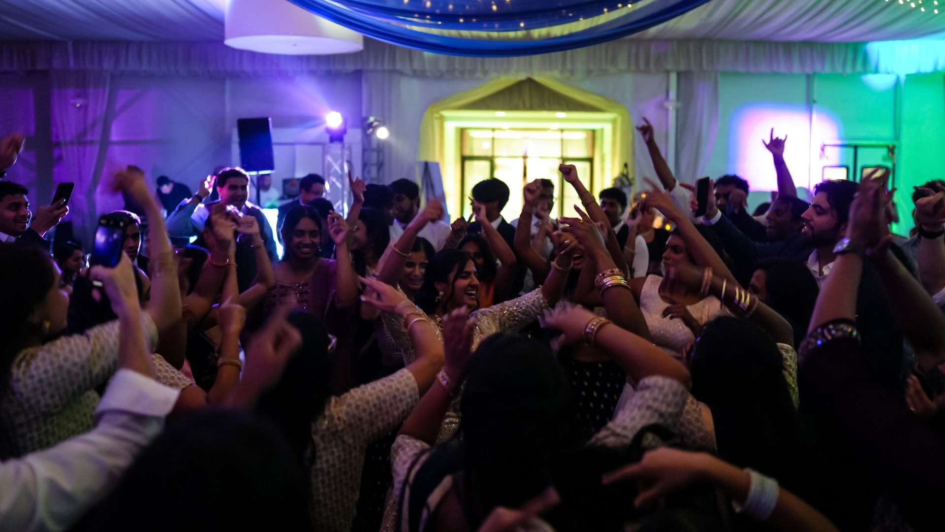 Guests on a packed dance floor with concert-style lighting — One Idea Entertainment